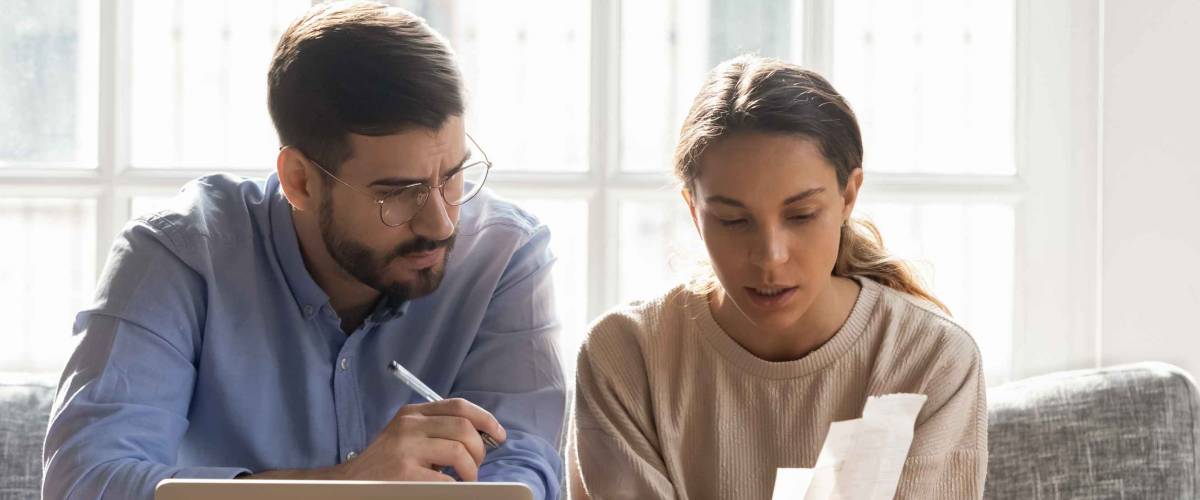 couple looks at papers while sitting on a couch