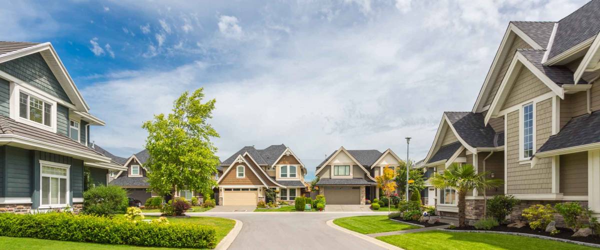 Nicely trimmed and manicured garden in front of a luxury house on a sunny summer day. Street of houses in the suburbs of Canada.