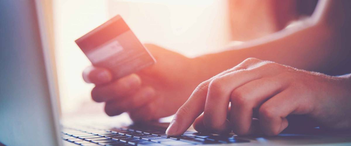 Hands holding credit card and using laptop