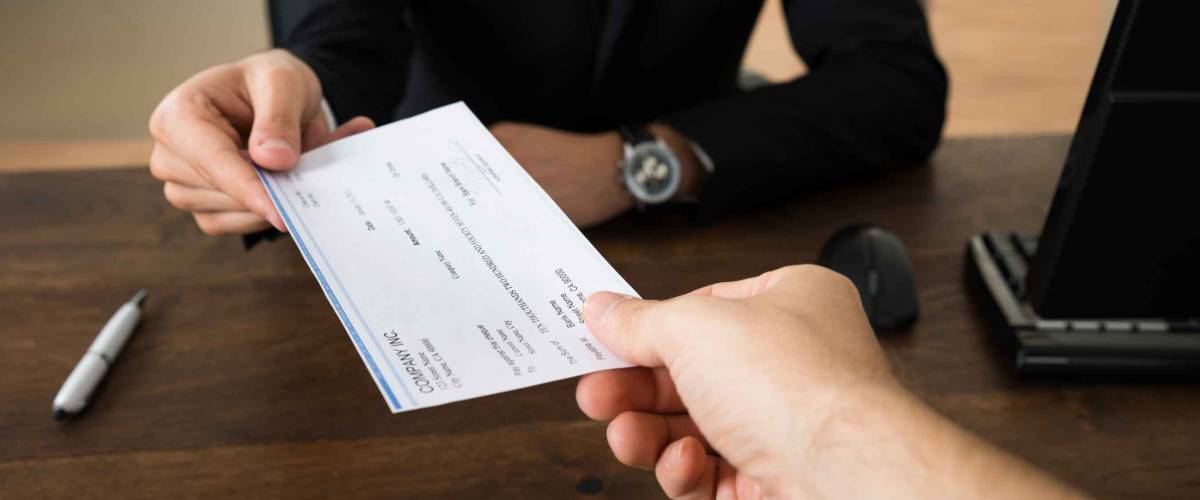 Close-up of man handing another person a cheque