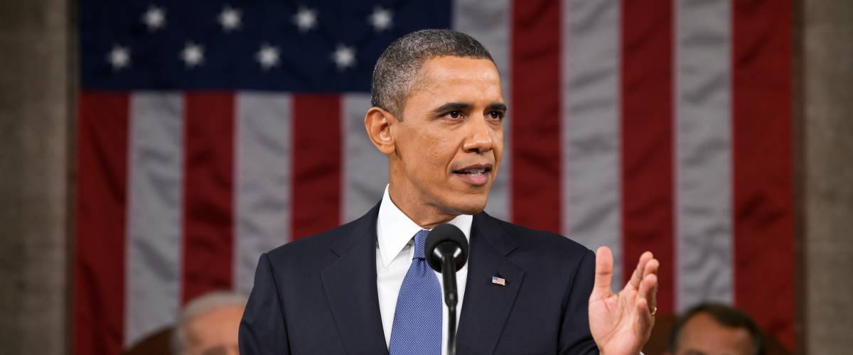 Barack Obama giving speech with American flag in the background