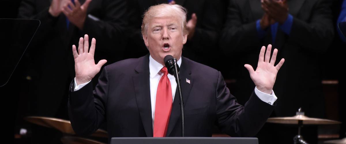 President Donald Trump speaks into microphone
