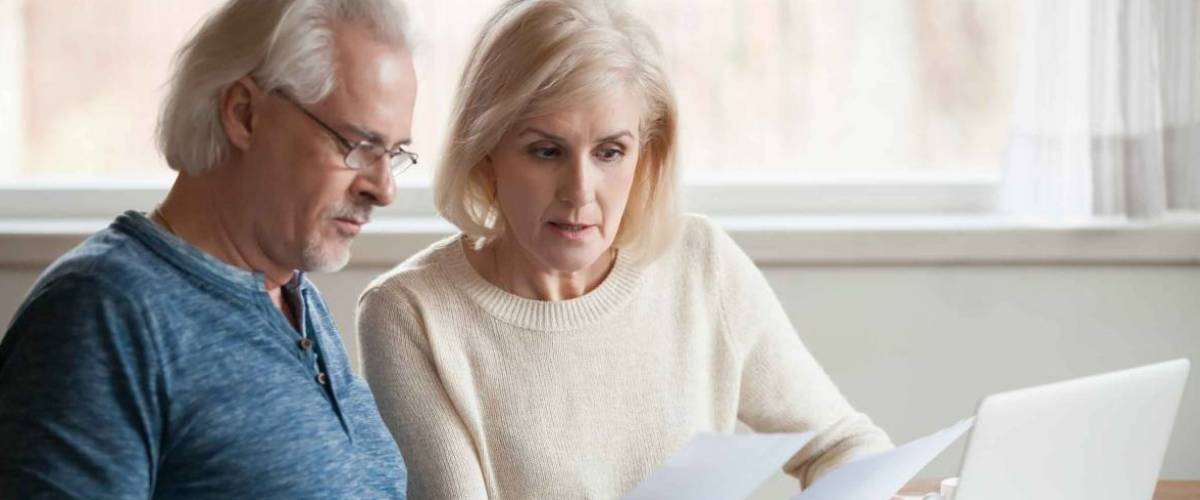 older couple looks at two different papers, look serious