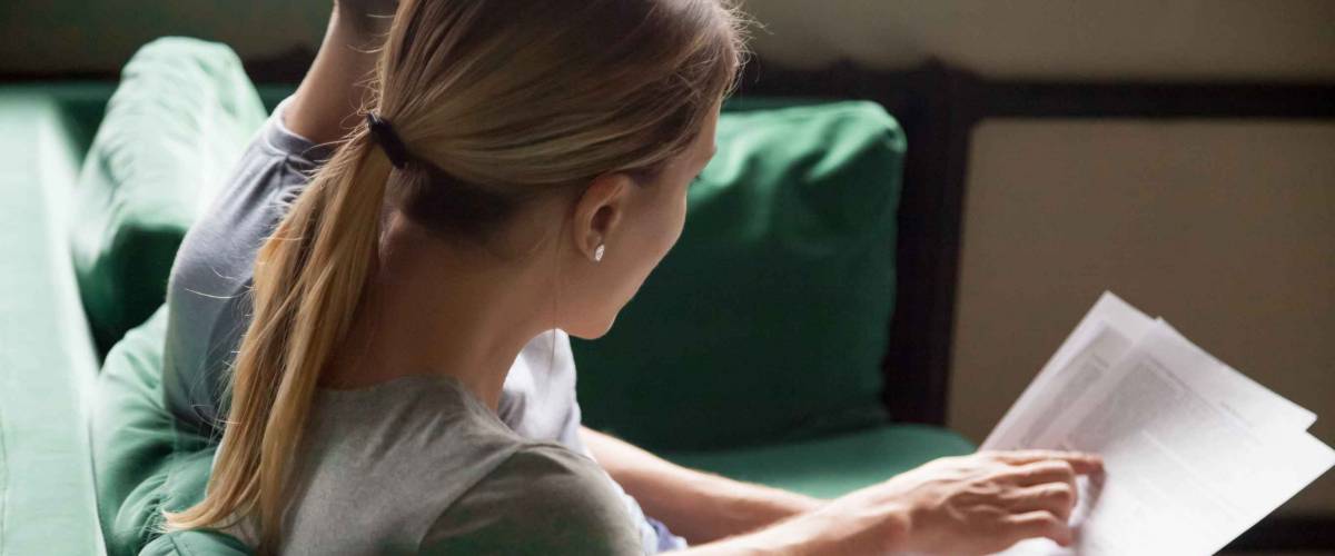 Couple looking at papers together, sitting on couch, shown from the side