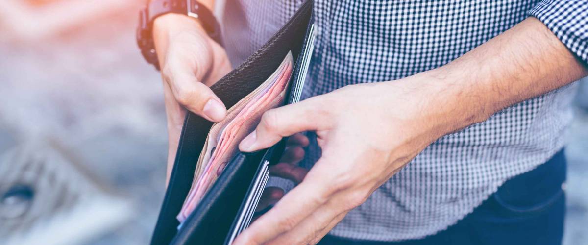 Man standing holding black wallet full of money
