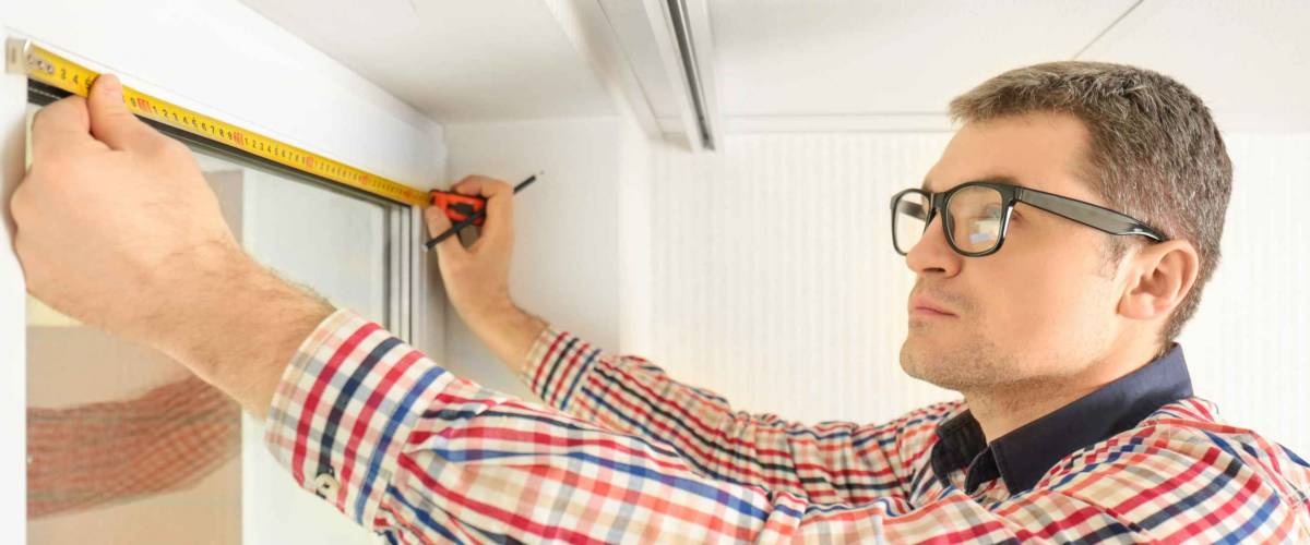 Young man installing window shades at home