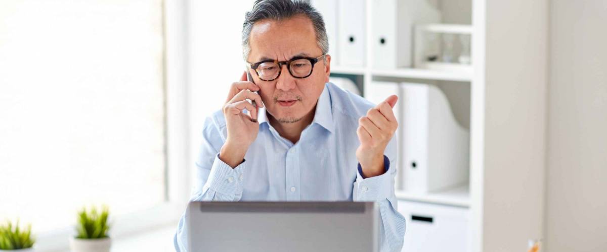 business, people, communication and technology concept - businessman with laptop computer calling on smartphone at office