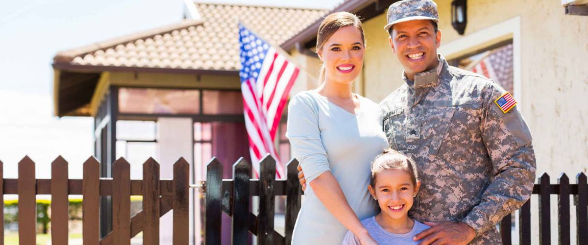 Veteran in fatigues with wife and daughter outside home