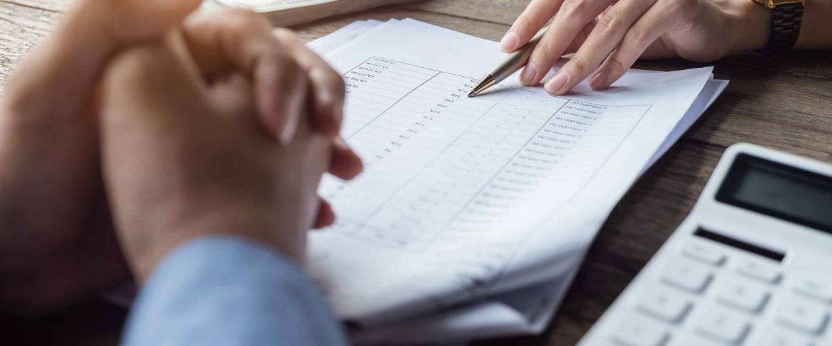 close up of two hands over papers and a calculator