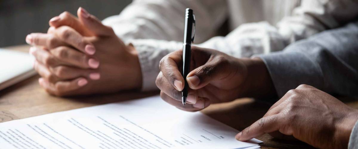 close up of man's hands signing papers