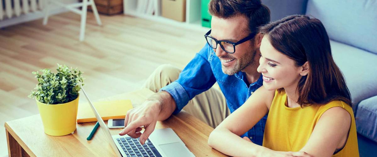 Happy couple with laptop spending time together at home