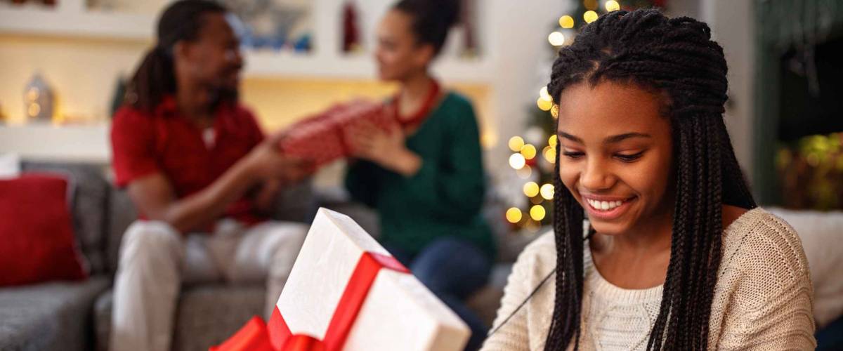 African young smiling girl opening box with Christmas gift
