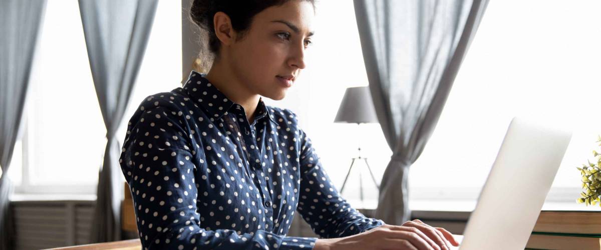 young woman looks serious, types at laptop