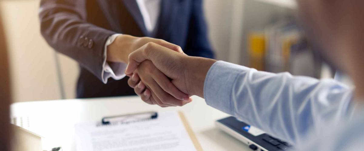 two men shake hands across a table