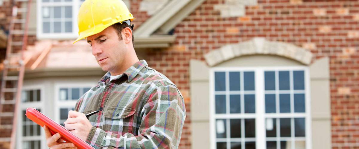home inspector stands in helmet outside home