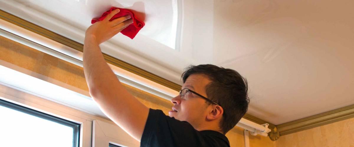 A man washes the ceiling using a rag. Cleaning service or activity during quarantine