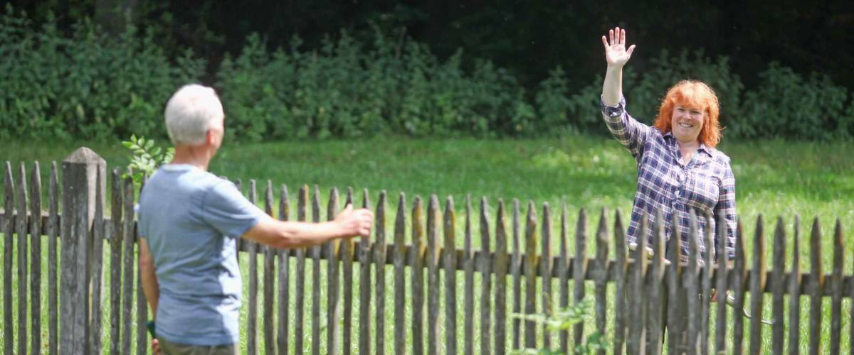 Neighbors greeting each other over fence