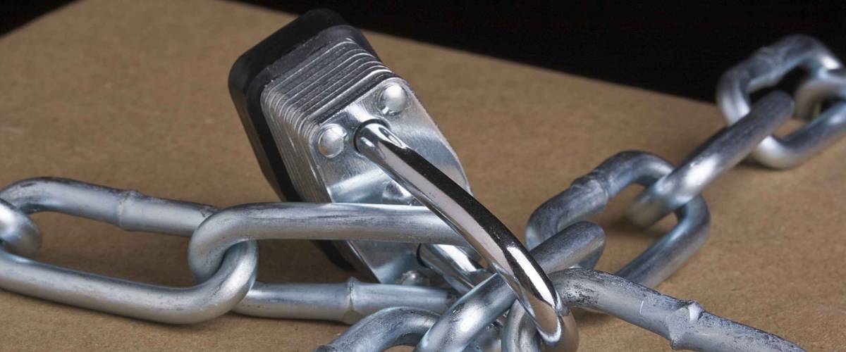 Metal lock and chain on a brown background.
