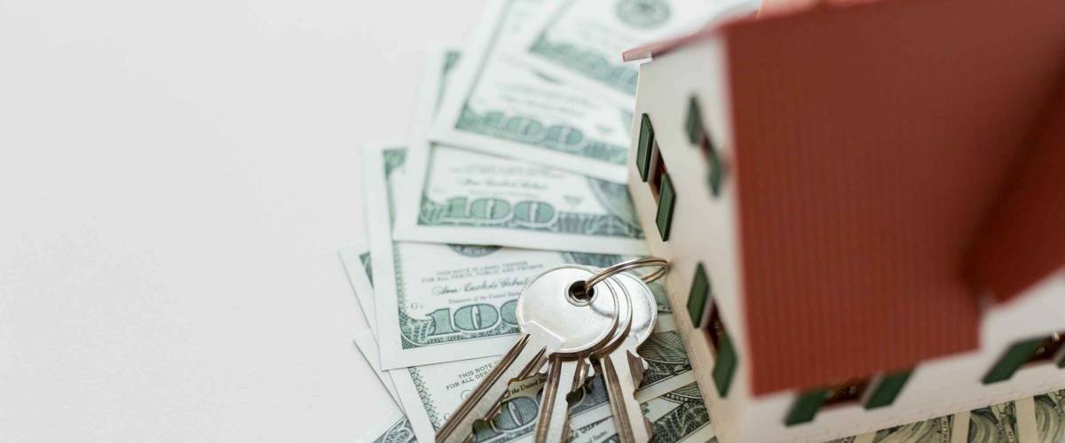 mortgage, investment, real estate and property concept - close up of home model, dollar money and house keys