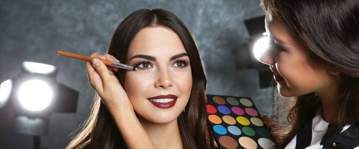 Professional makeup artist working with beautiful young woman