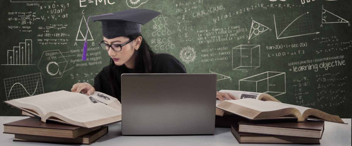 Busy female graduate doing her research with laptop in class
