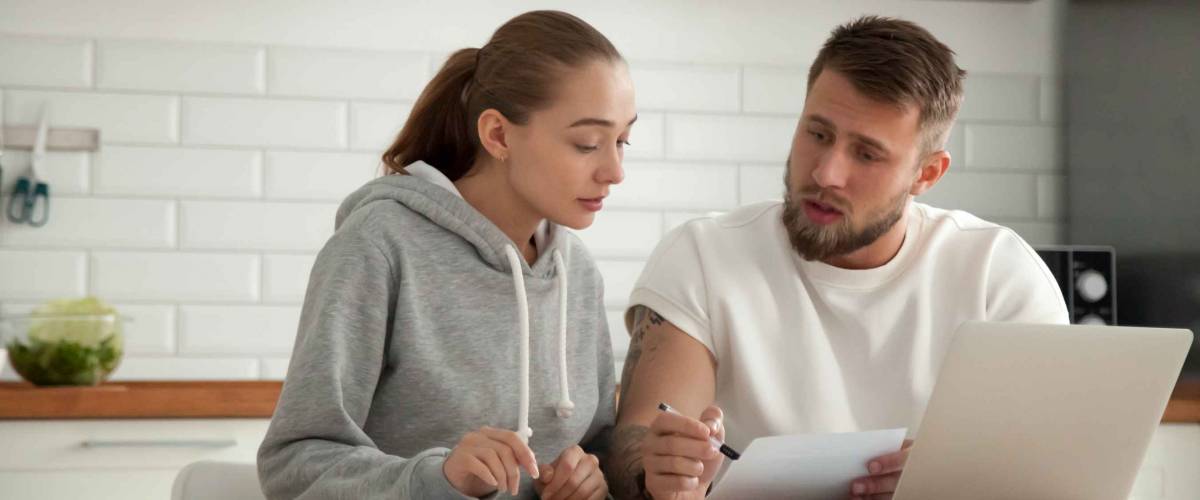 Focused young couple looking at bills at the kitchen table