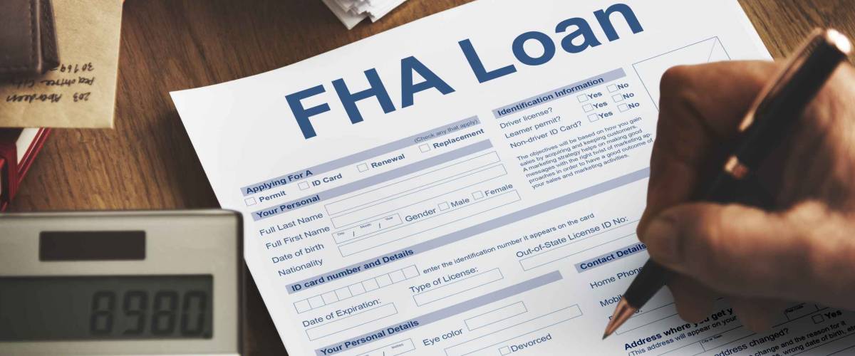 FHA Loan sheet with person holding pen over it, calculator to the side