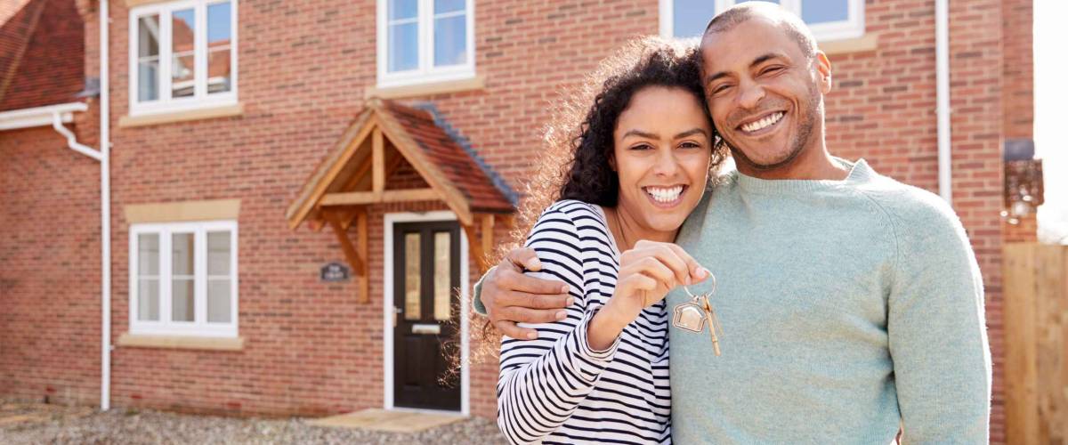 Portrait Of Couple Holding Keys Standing Outside New Home with Keys
