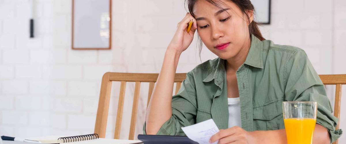 Stressed Asian woman serious and argument when calculate home financial bill budget on table in kitchen at new house