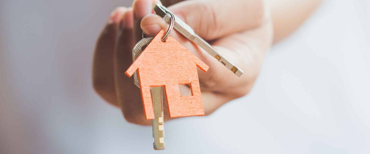 Female hand holding house key,real estate agent.