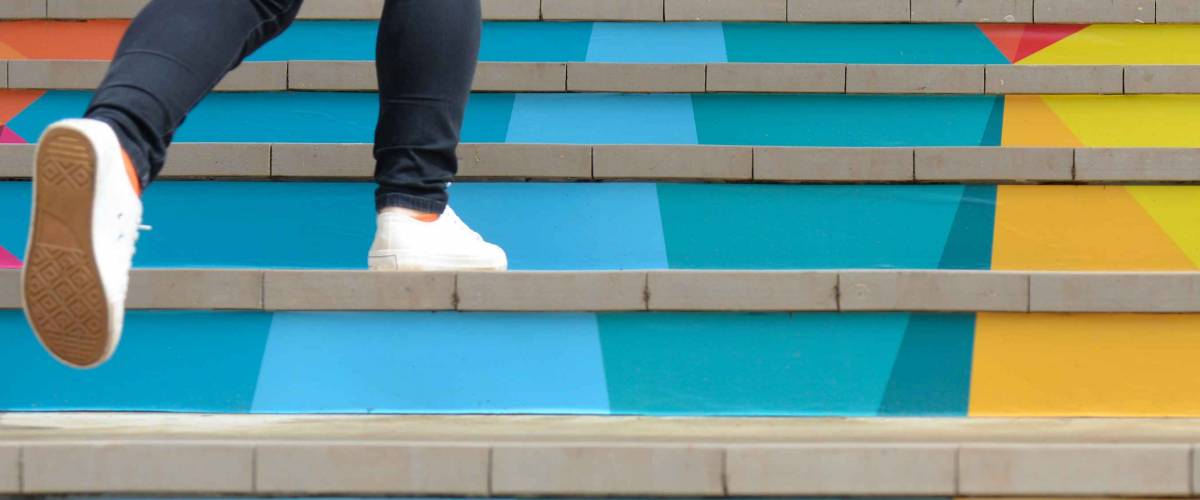 Lower part of teenage girl in casual shoe walking up outdoor colorful stair,teenage lifestyle successful concept