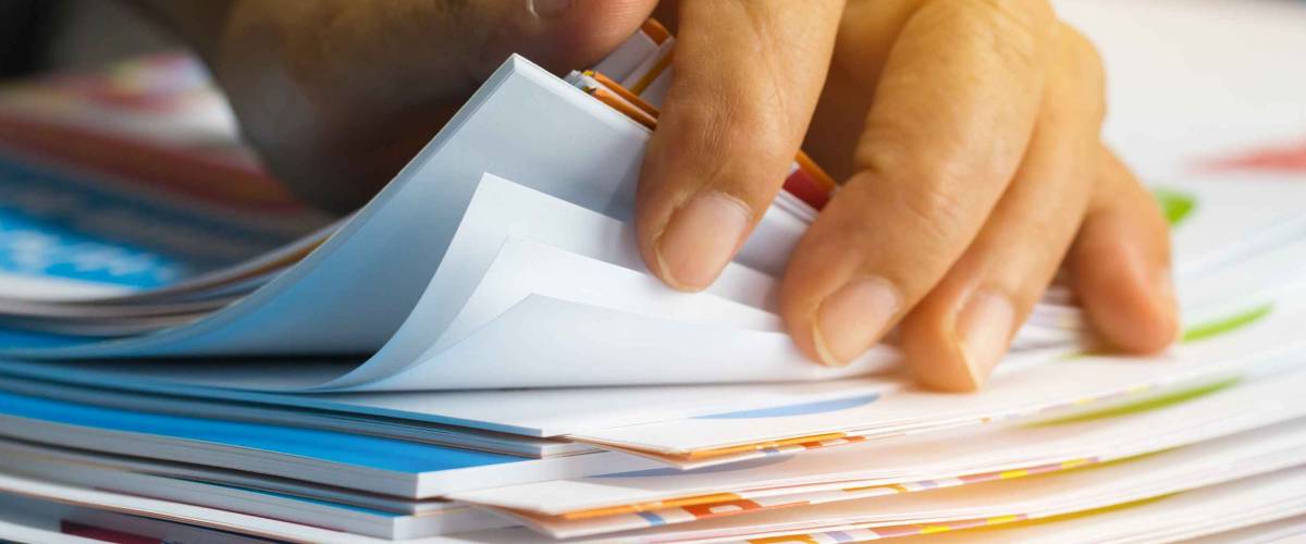 Businessman hands searching unfinished documents stacks of paper files on office desk for report papers, piles of sheet achieves with clips on table, Document is written, drawn,presented.