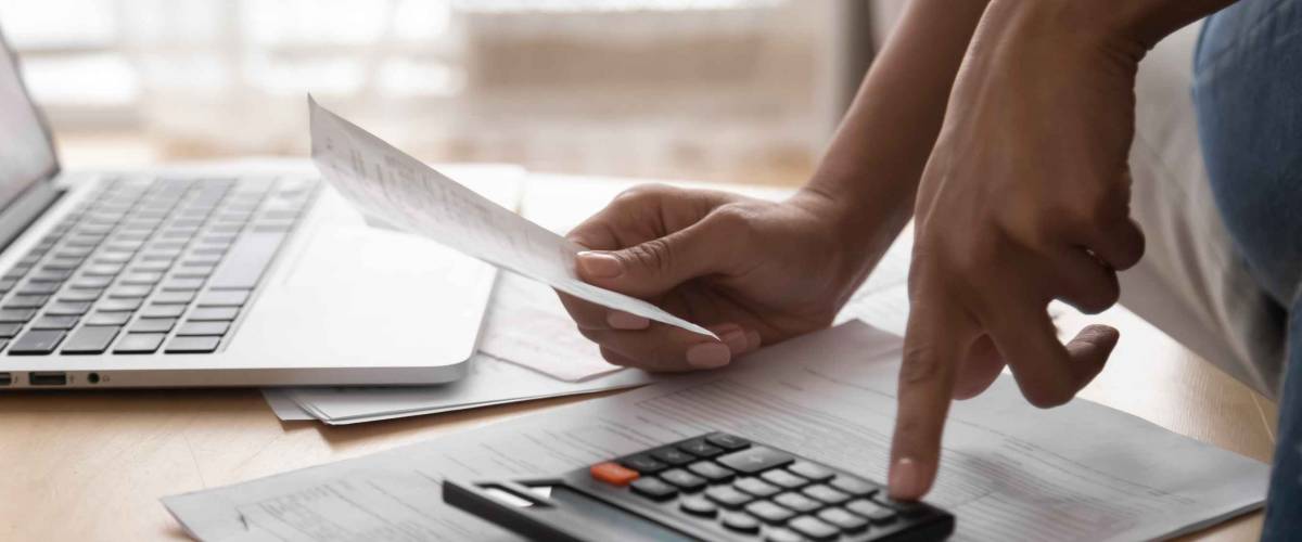 African woman holding paper bills using calculator, close up vie