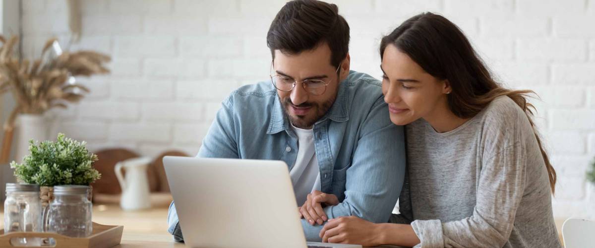 smiling man and woman look at laptop intently