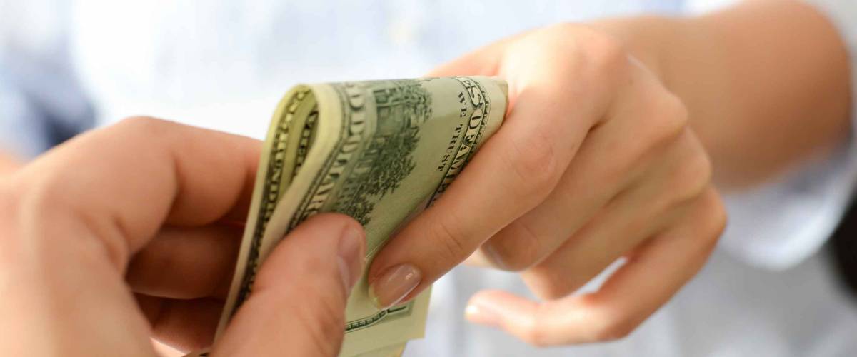 two hands exchanging American bills