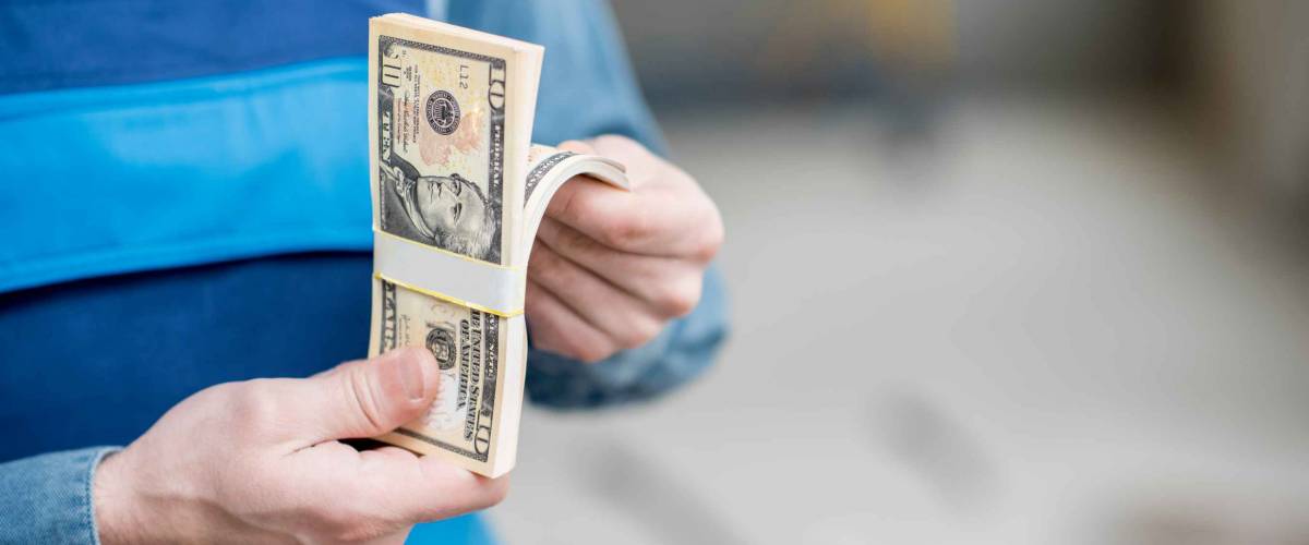 Man holding a stack of American bills, counting it in his hands