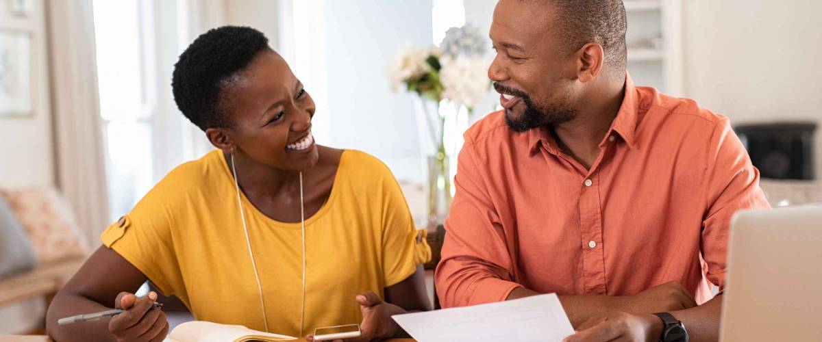 Man and woman smiling at each other, looking at sheets of paper at table