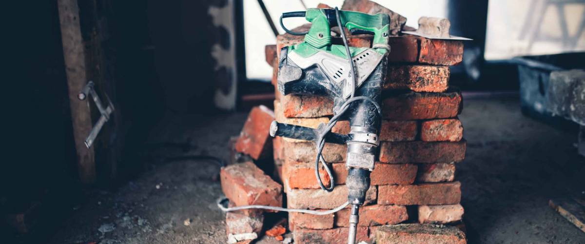 Pile of red bricks with jackhammer placed in front of it