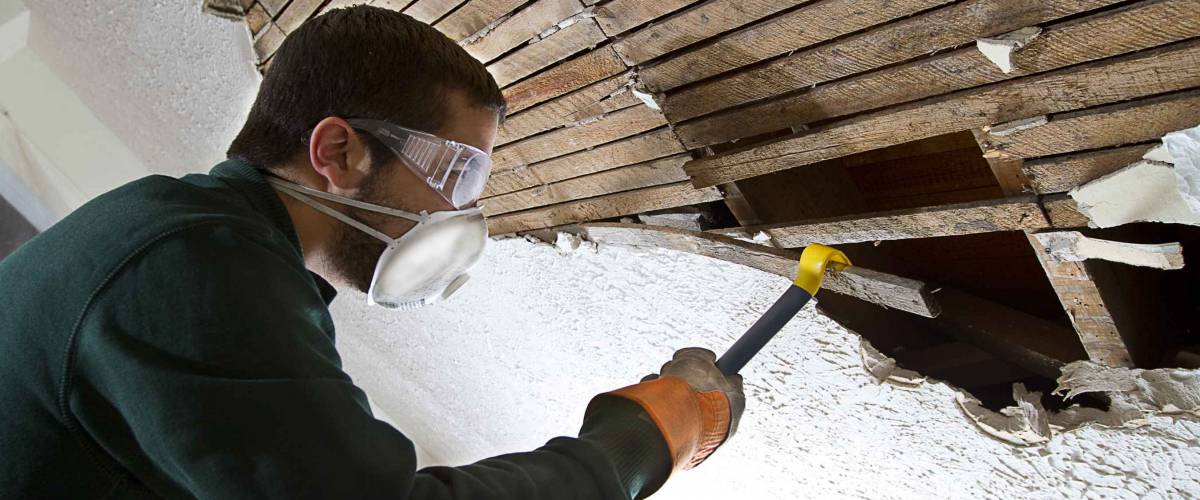 Ceiling Demolition man removing plaster lathe from ceiling with a crowbar