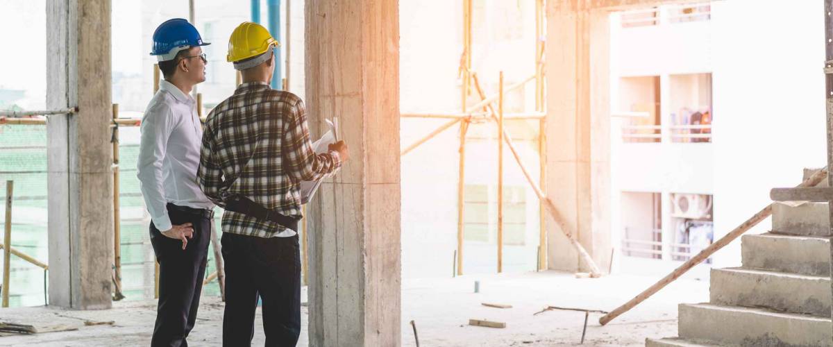 Two men in hard hats looking at home under construction