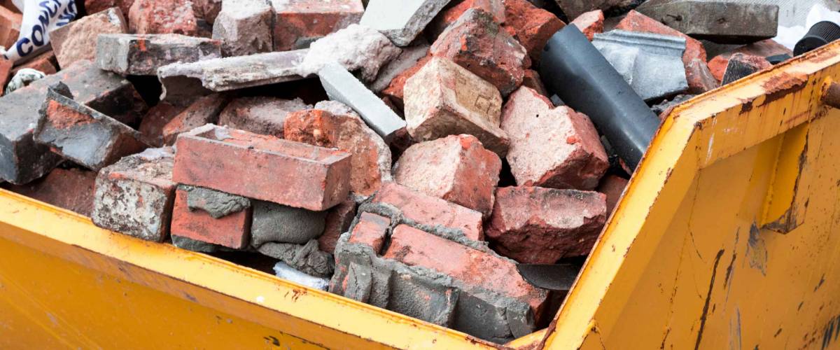 Yellow metal skip full of old bricks