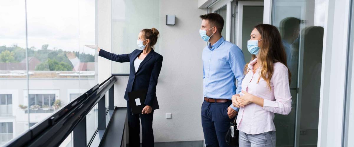 Happy Couple Buying New Home With Realtor Wearing Face Masks
