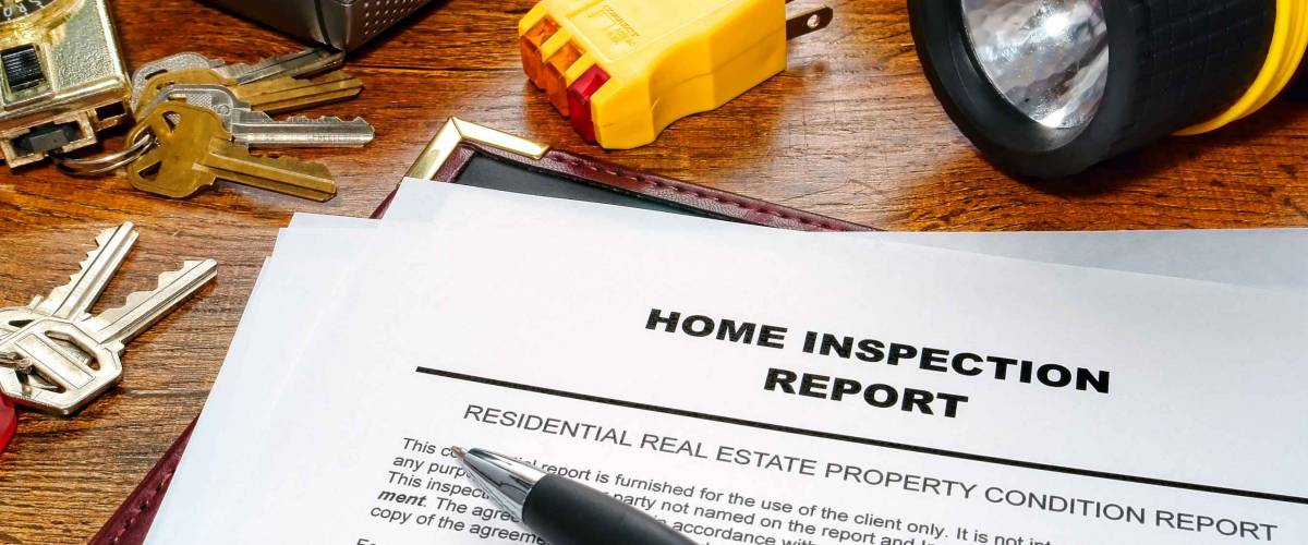 Real estate home inspection report with pen, flashlight and keys nearby