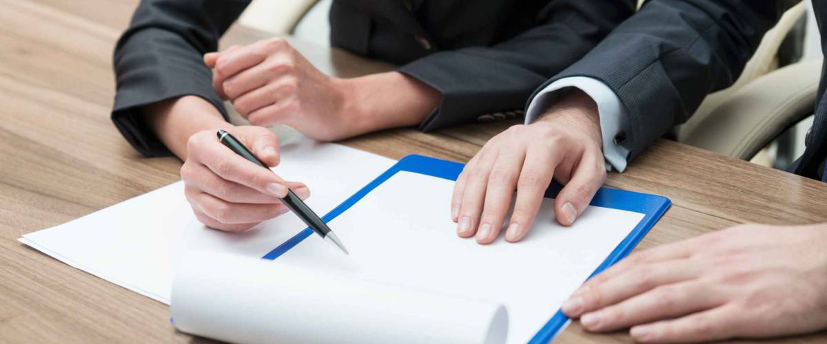 Close up of man and woman with hands on document, woman holding pen
