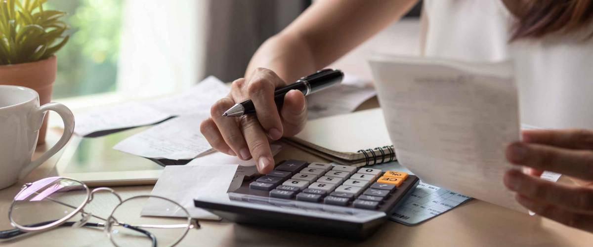 Close up of woman holding receipts and using calculator