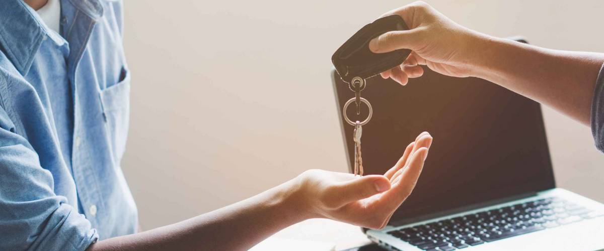 Close up of person handing keys to someone with an outstretched hand
