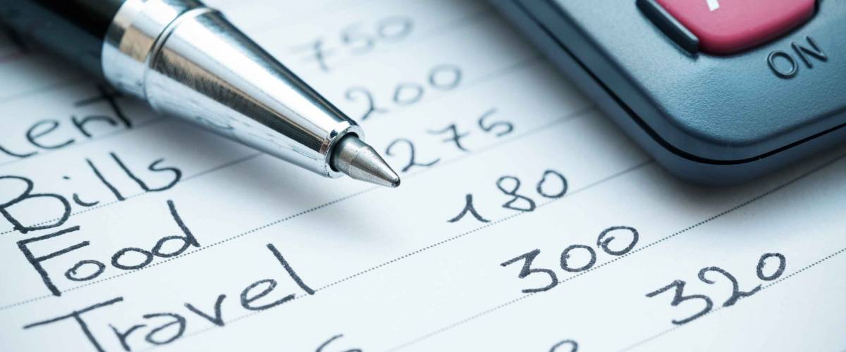 Home expenses list with calculator and pen on top