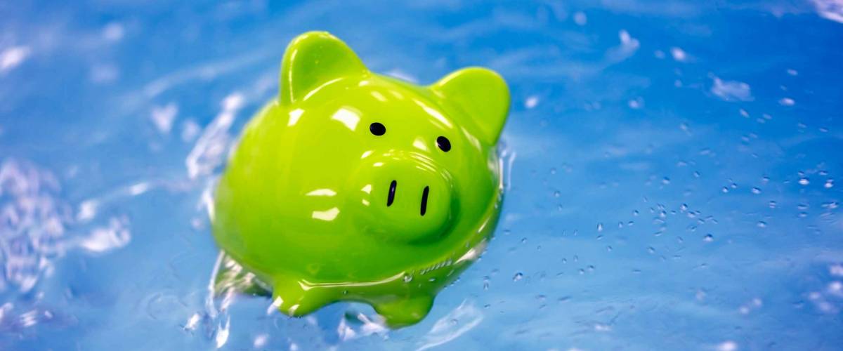 Piggy bank drowning in debt sinking in water concept for bankruptcy and business financial crisis