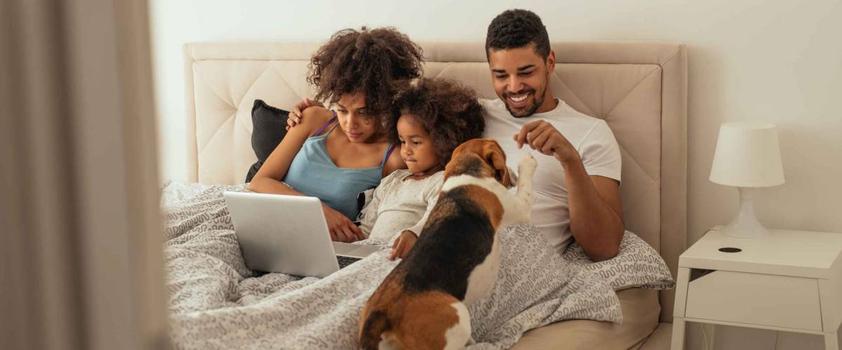 Happy family playing with their dog in bed.