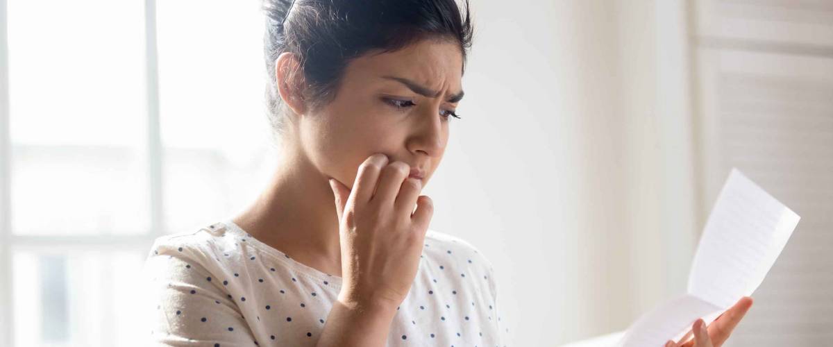 Worried millennial girl looks at bills